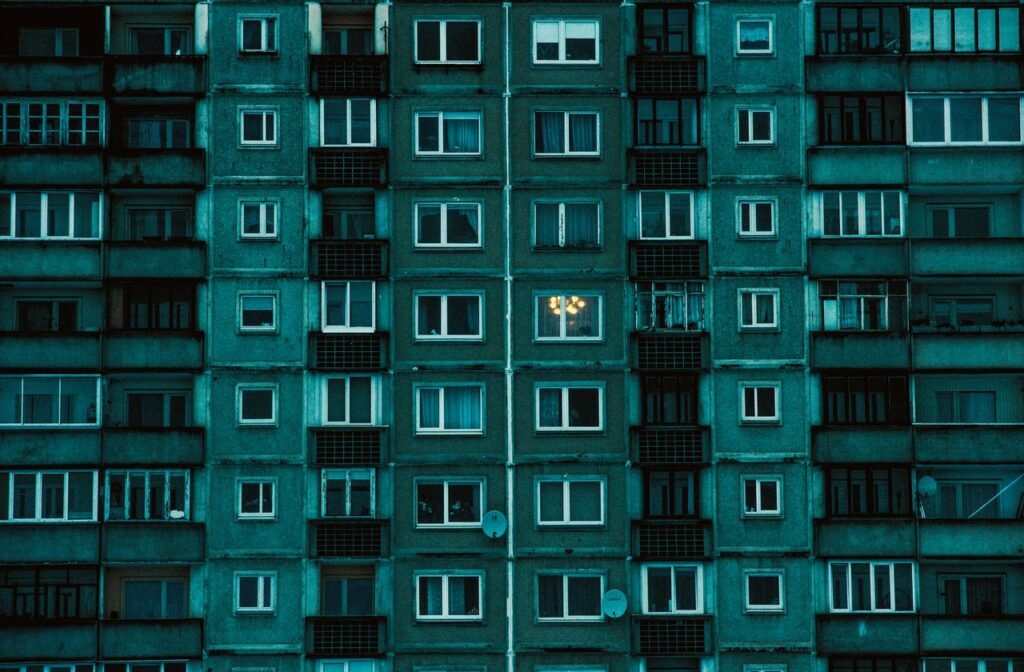 Detailed view of a symmetrical urban apartment building facade with a cold color palette.